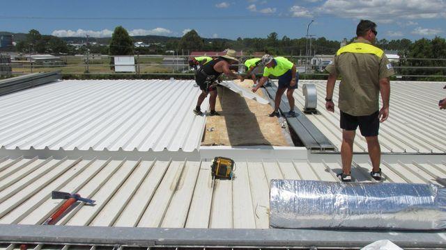 Photo of workmen on a commercial roof. We give quotes for roofing repairs, replacements & restorations on commercial buildings.