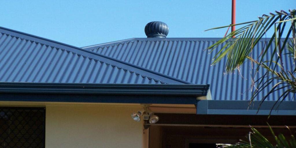 A photo of a residential house, focusing on the recently restored dark grey metal roof - a expert roofing service provided by MTEC Roofing & Guttering.